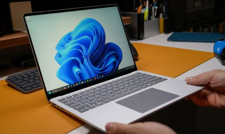 Persona sosteniendo un portátil con Windows 11 sobre un escritorio